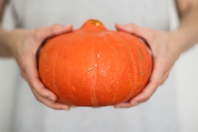 Hands holding a bright orange pumpkin